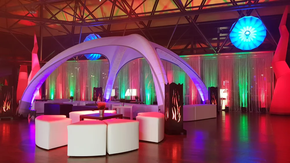 Beleuchteter Lounge- und Barbereich mit Eventmobiliar am Abend