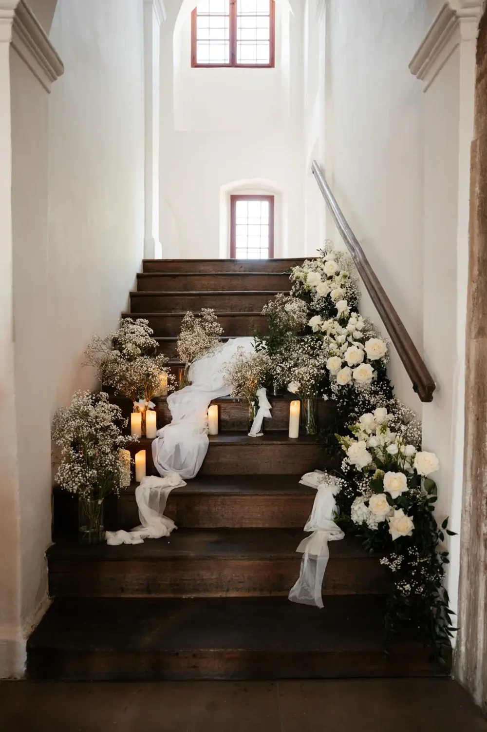 Florales Arrangement aus Rosen, Schleierkraut und Kerzen auf einer Treppe