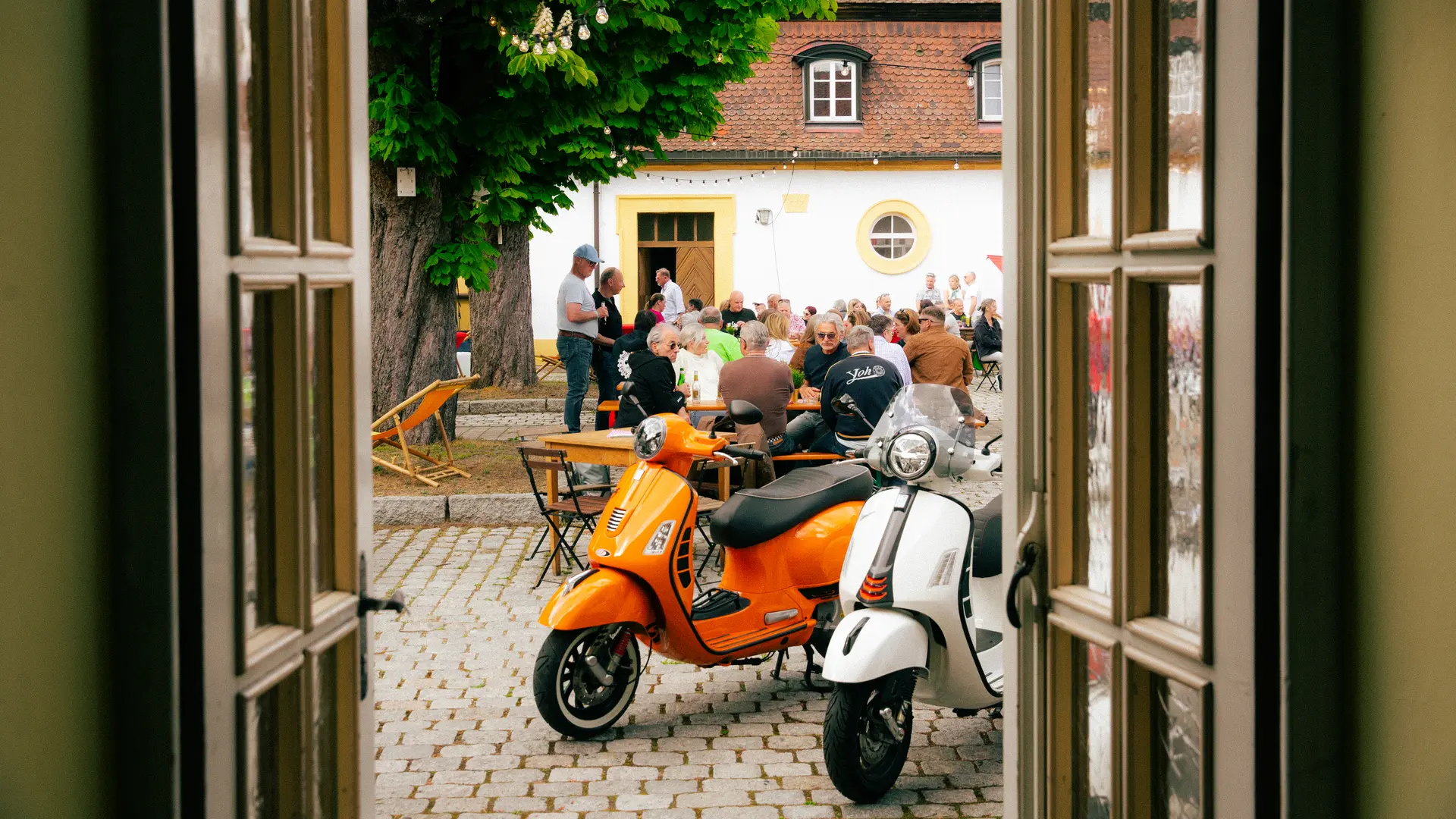 Blick durch die Schlosstür auf Vespas und Gäste